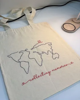 Bolsa de tecido bordada por aluna com mapa-múndi, avião e a frase collecting memories