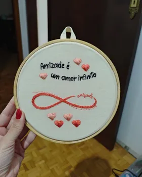 Bordado de aluna em bastidor com corações, símbolo do infinito e a frase Amizade é um amor infinito