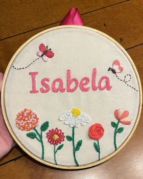 Bordado de aluna em bastidor com o nome Isabela, borboletas e flores coloridas